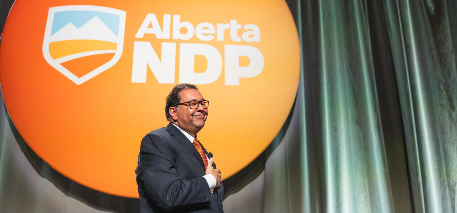 Nenshi standing in front of an Alberta NDP sign
