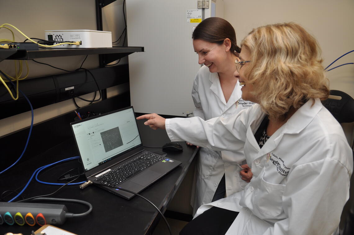 Instructor showing student work on laptop.